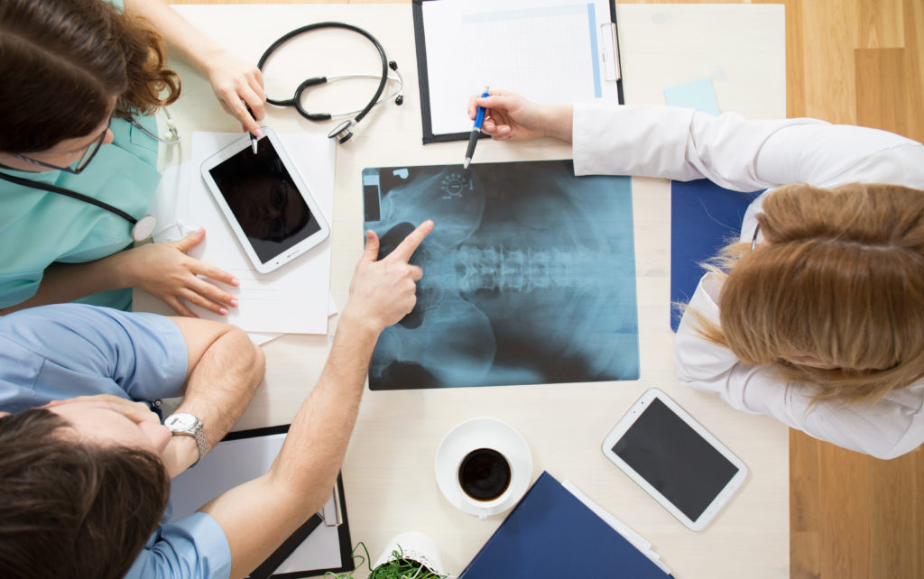 Instructor and students sitting around the table and interpreting x-ray image